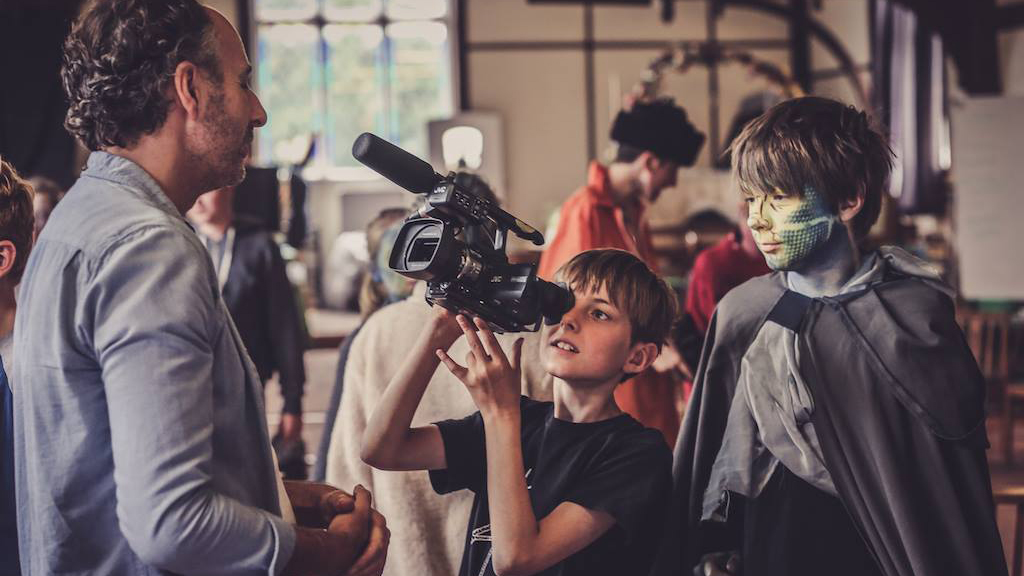 A young boy points a film camera at the teacher at Summer Film School