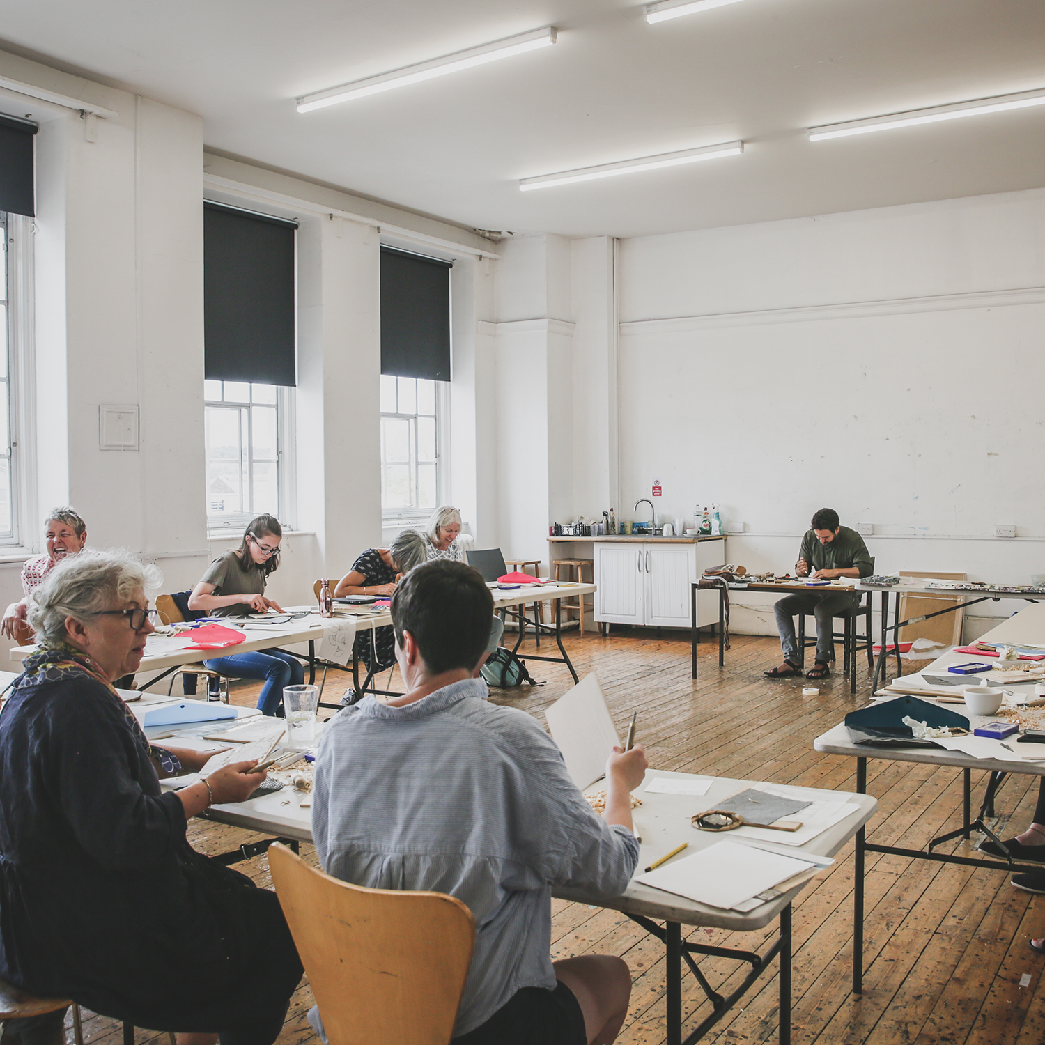 A group of 6 people in the middle of an art workshop.