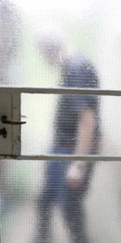 A man's silhouette behind a blurry glass door.