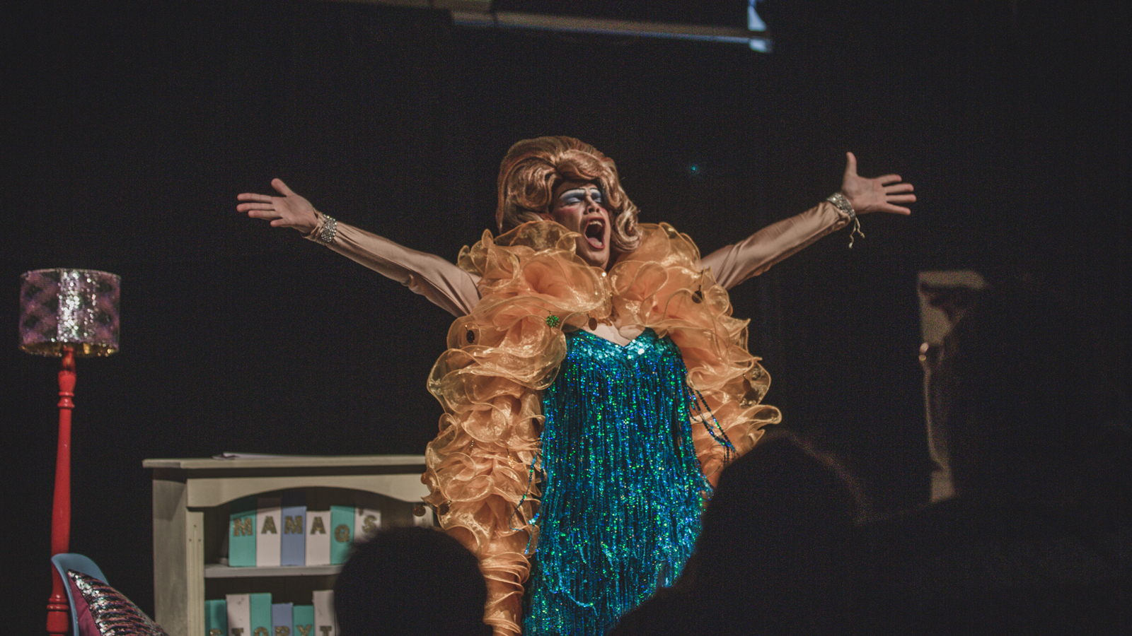 Drag queen Mama G performs in Studio 1 in a blue sequinned dress and orange feather boa