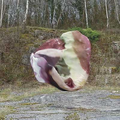 A screenshot from Isobel's film 'We Few'. A ball of fabric floats in the middle of some rocky surroundings.