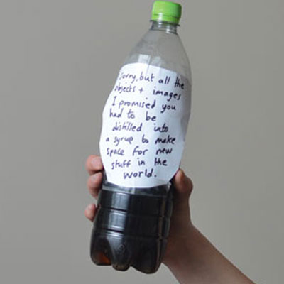 A hand holds up a plastic bottle half filled with syrup.