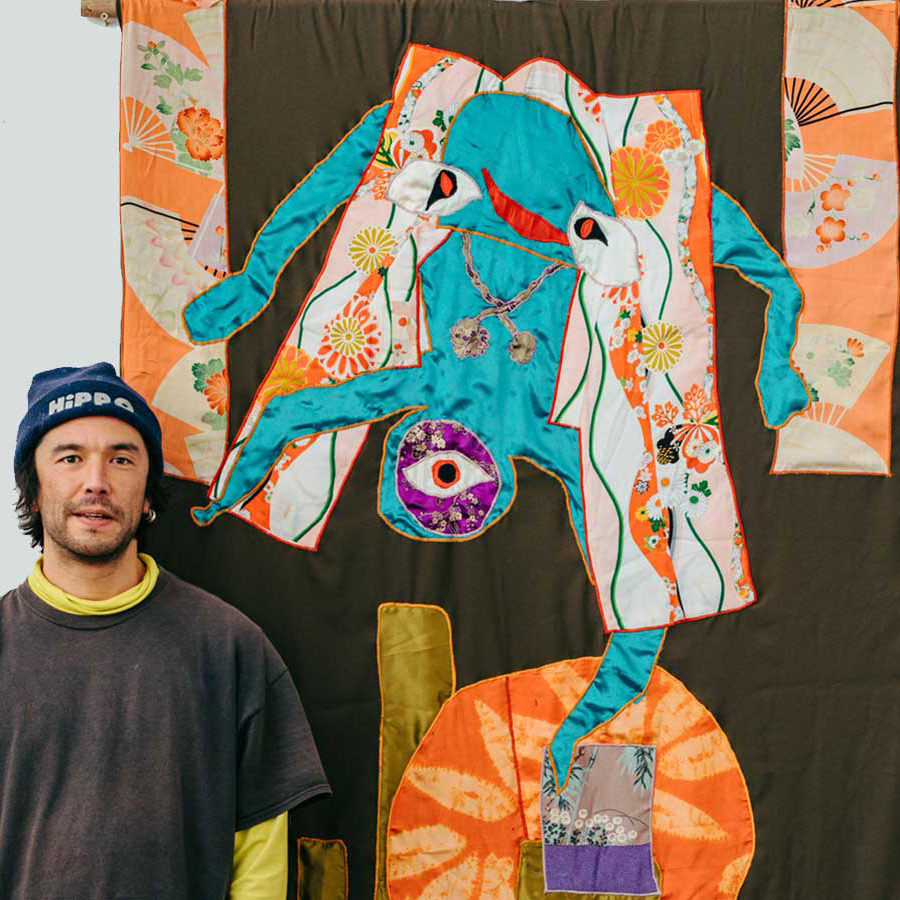 Artist Huhtamaki Wab stands besides one of his tapestries.