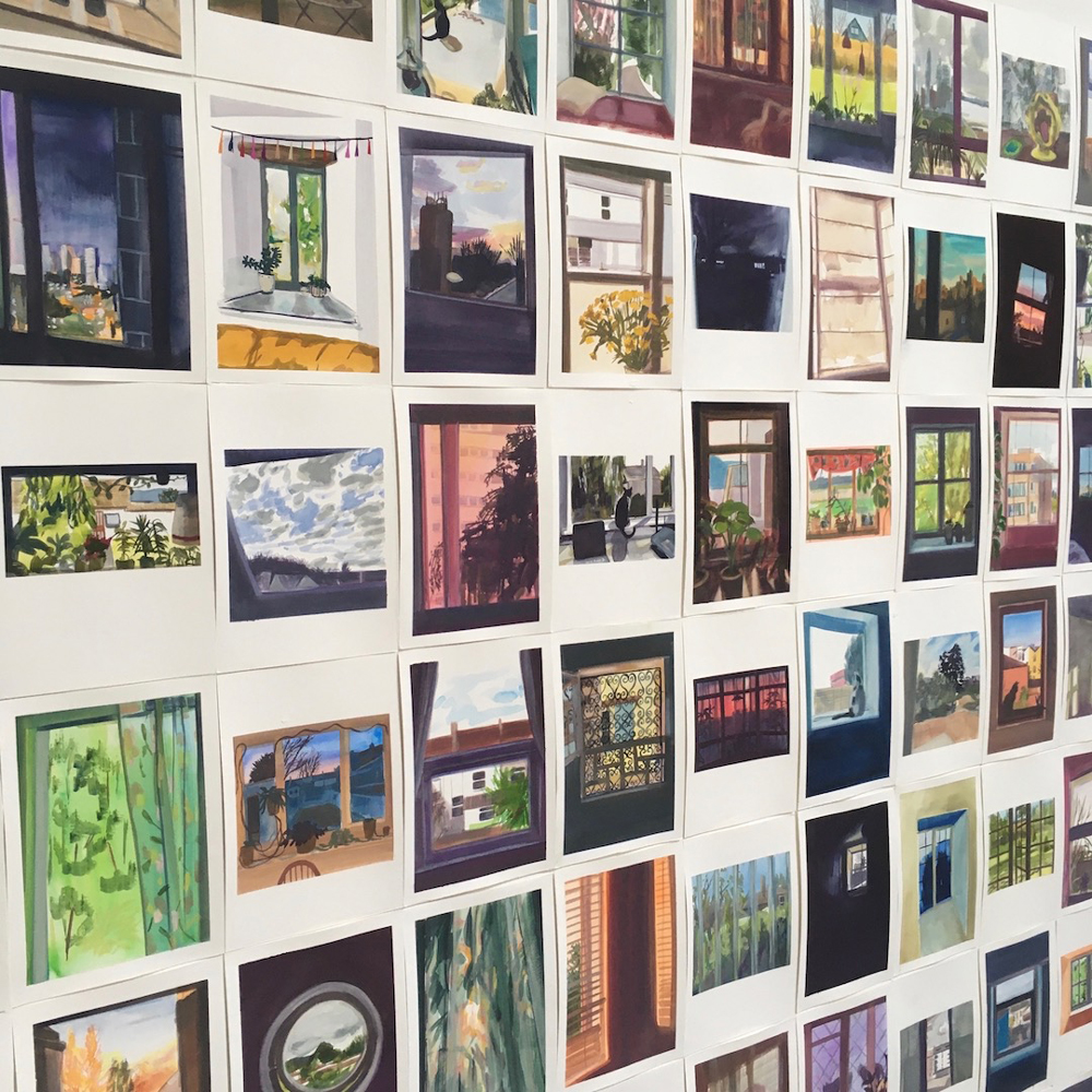 A photograph of around 25 framed photographs of windows hanging on a white wall