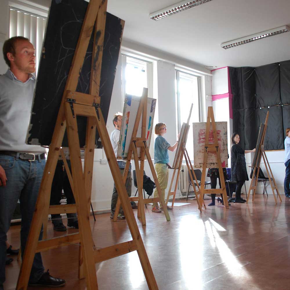 A group of artists stand next to easels.