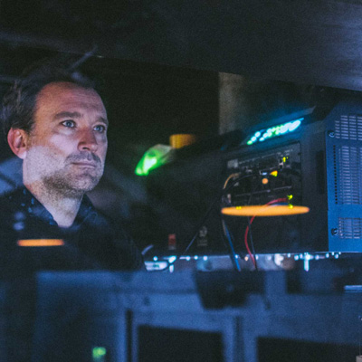 A photographer of Jonas Hawkins in the dmly lit projection box at Exeter Phoenix