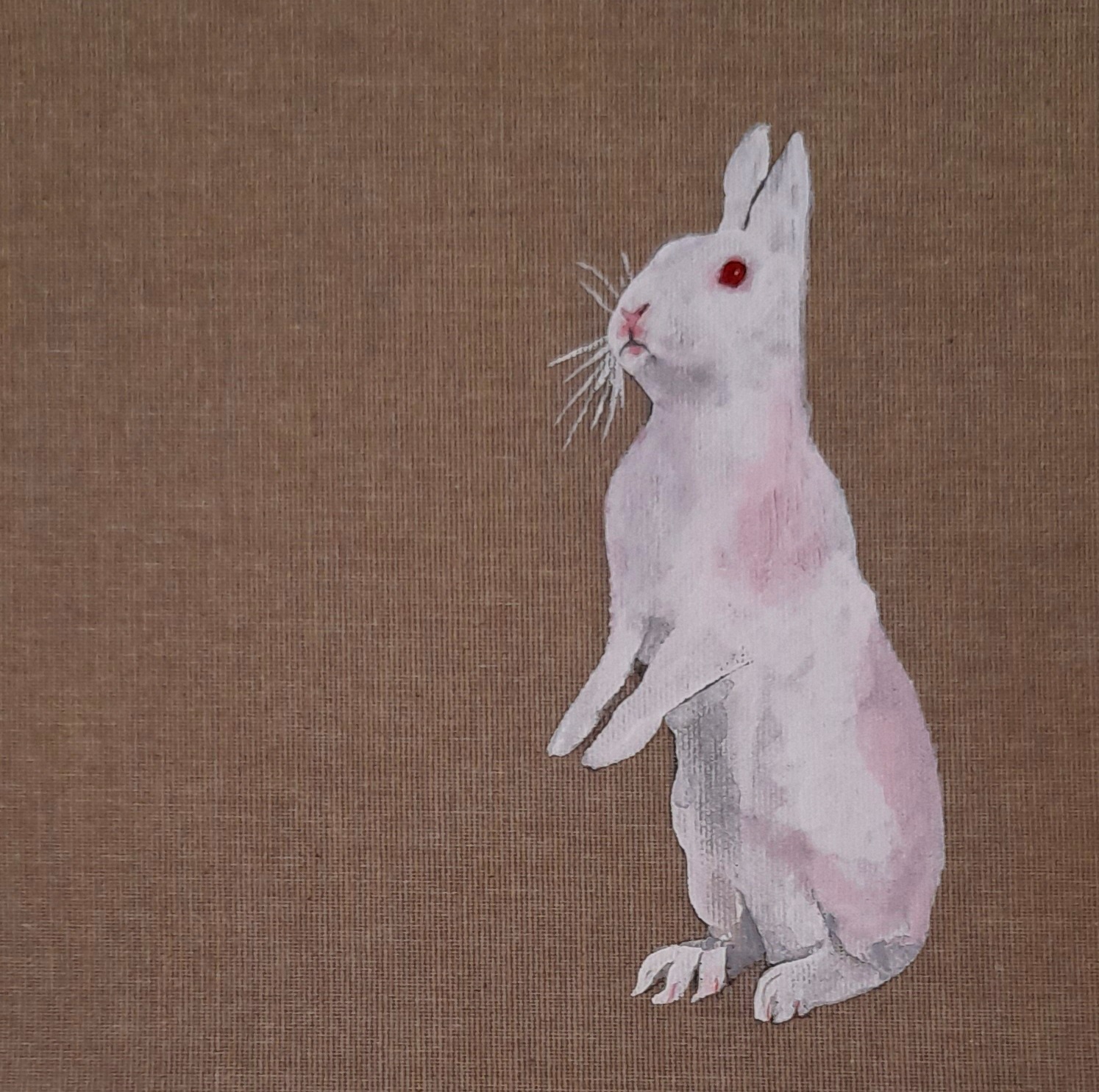 A white bunny rabbit stands on its hind legs on the right half of a brown canvas.