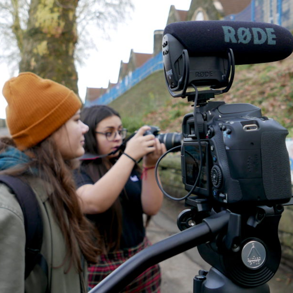 Image of two young filmmakers operating a film camera on set