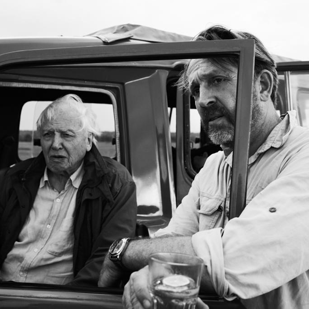 A black and white image of David Attenborough and Toby Strong in a jeep