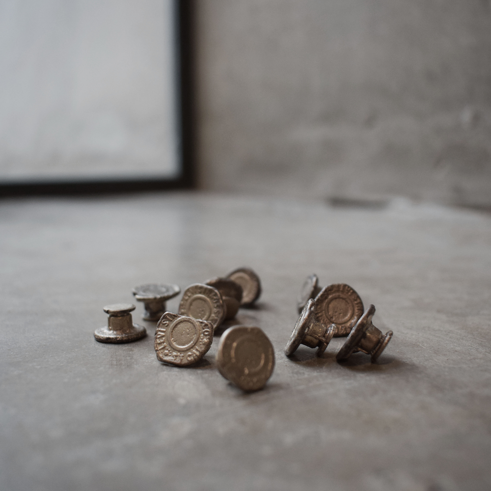 A small collection of jean button-shaped objects, that also look old and worn like old coins.