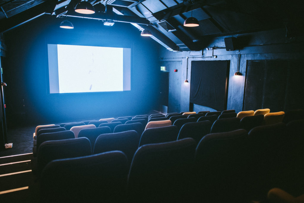 An empty cinema with a bright white screen
