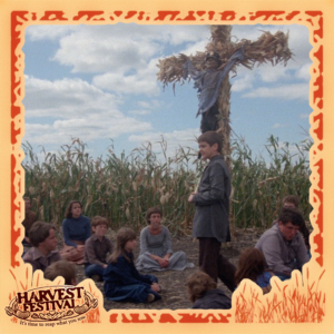 A group of children sat in a corn field next to a corn cross