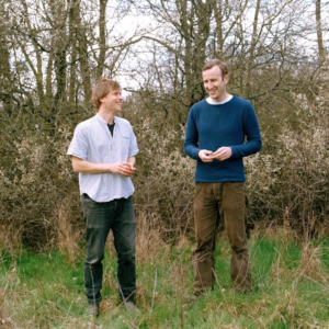 Musician Johnny Flynn and Author Robert Macfarlane stood in a field