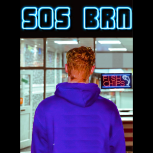 A man Stood in front of a fish and chip shop with neon lighting saying 'SOS BRN'