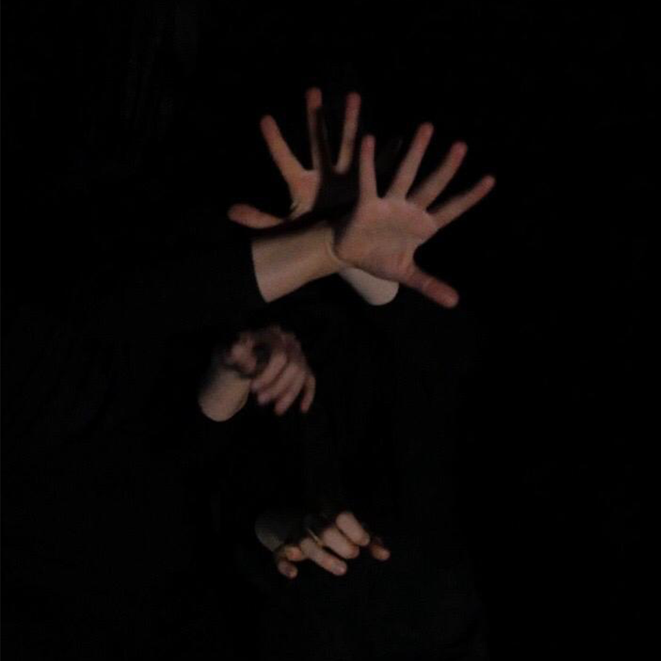Hands splayed out in a group emerging from the dark