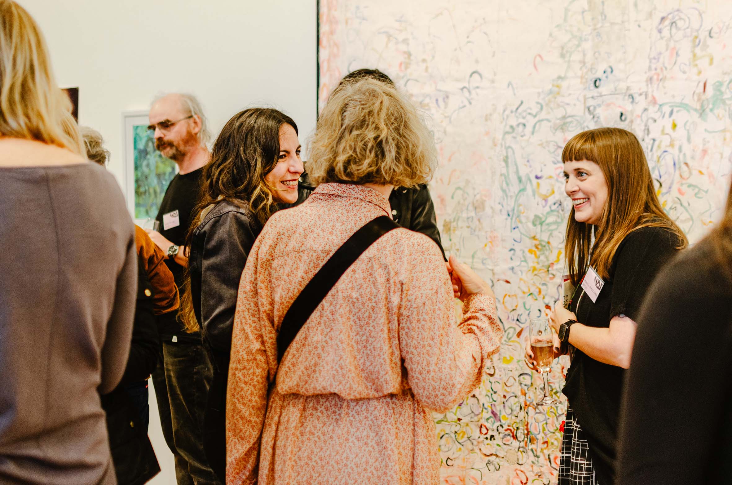 A group of people stood infront of a large abstract painting discussing