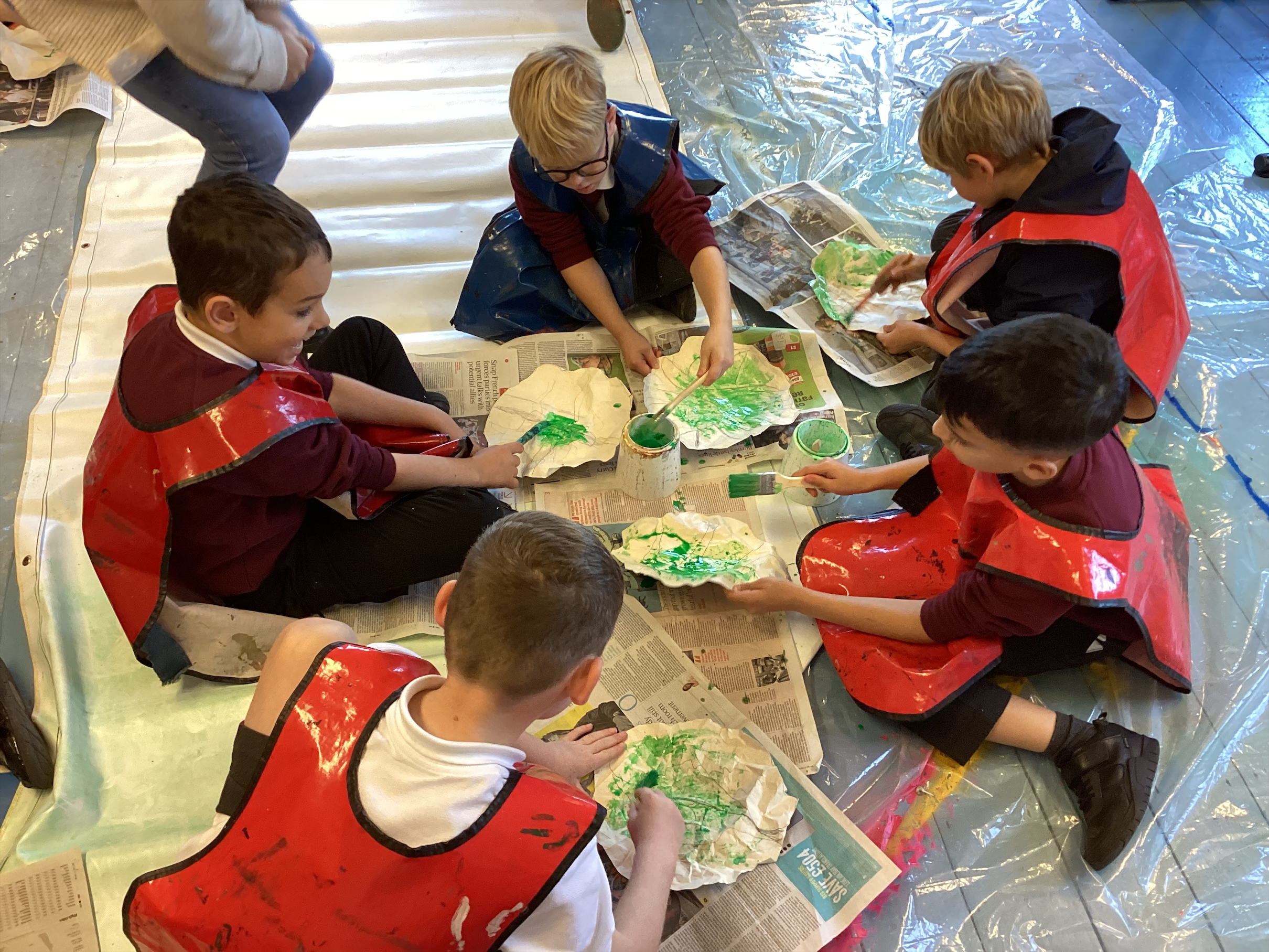 Some small children sat on the floor painting circles green