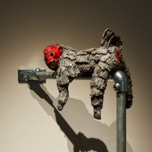 A ceramic monkey lying on top of a metal pole